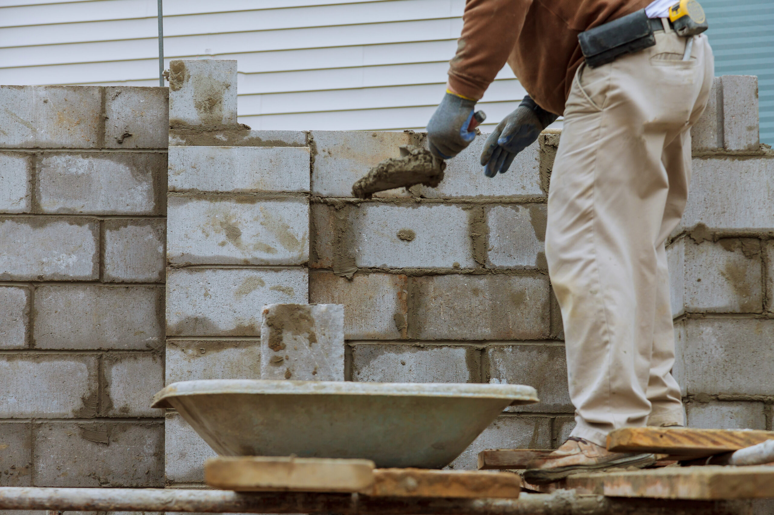 Construction worker laying of concrete blocks bricklaying new house wall on foundation